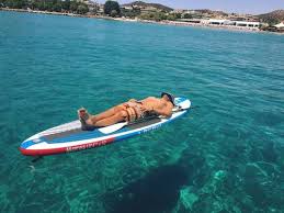 man resting on a paddleboard over a reef