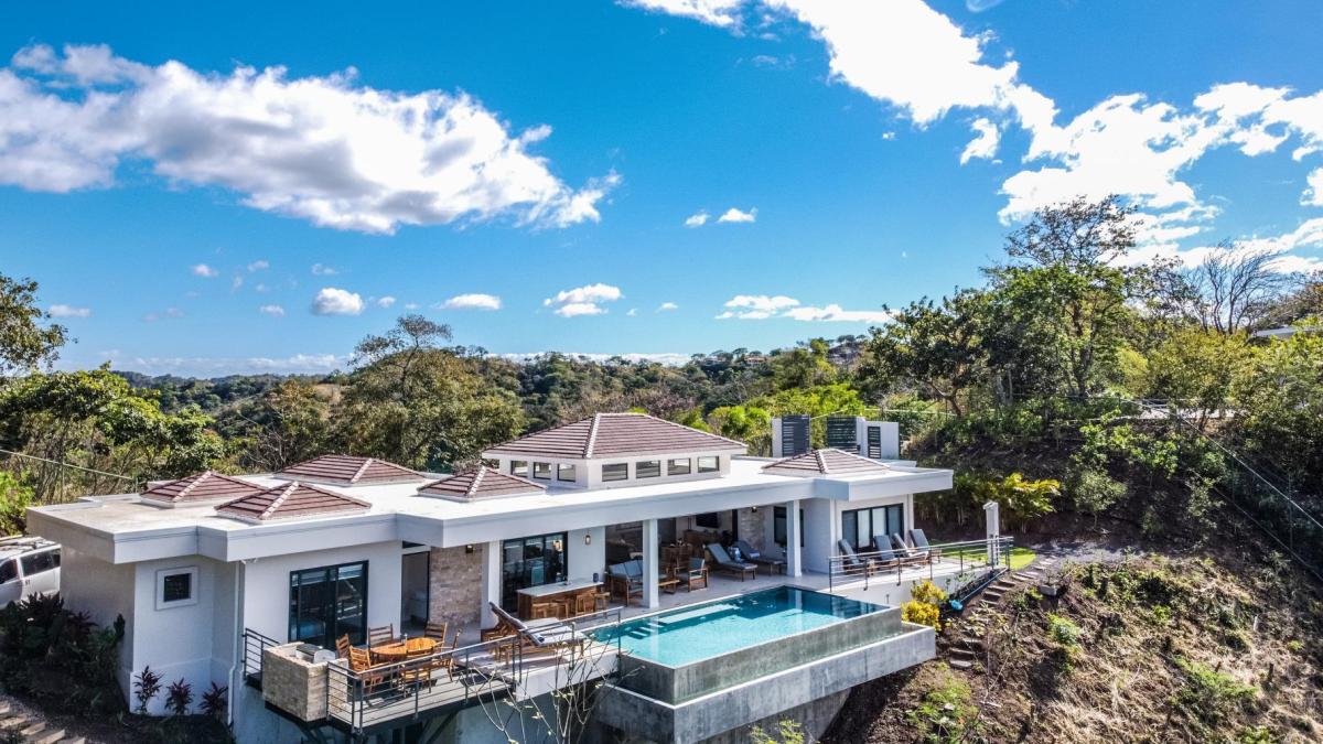Aerial view of a luxury home with an infinity pool on a hillside overlooking Playa Hermosa in Costa Rica