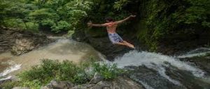 Person diving into a pool below a waterfall in Costa Rica